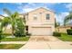 Two story house with beige exterior, two car garage, and palm trees at 409 Serenity Mill Loop, Ruskin, FL 33570