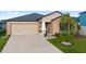 Tan house with a two-car garage and landscaping at 10005 Caraway Spice Ave, Riverview, FL 33578