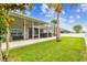 An enclosed, screened-in outdoor living area with a hot tub surrounded by a green yard with a palm tree at 6843 Boulder Run Loop, Wesley Chapel, FL 33545