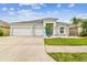 Inviting home featuring a well-kept lawn, beautiful landscaping with palm trees, and a three-car garage, showcasing curb appeal at 6843 Boulder Run Loop, Wesley Chapel, FL 33545