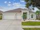 Inviting home with vibrant blue door, manicured lawn, and spacious two-car garage at 6843 Boulder Run Loop, Wesley Chapel, FL 33545