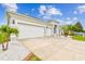 Elegant home featuring a three-car garage, a spacious driveway, and manicured landscaping with palm trees at 6843 Boulder Run Loop, Wesley Chapel, FL 33545