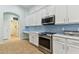 Bright, modern kitchen features white cabinets, stainless steel appliances, and a light blue backsplash at 6843 Boulder Run Loop, Wesley Chapel, FL 33545