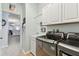 Modern laundry room with stainless steel washer/dryer, utility sink and neutral walls and white cabinets at 6843 Boulder Run Loop, Wesley Chapel, FL 33545