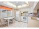 Kitchen features white cabinets, stove, refrigerator, and breakfast nook at 3332 Scorecard Dr, New Port Richey, FL 34655
