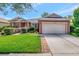 Single-story home with two-car garage, lush lawn, and brick walkway at 10906 Holly Cone Dr, Riverview, FL 33569