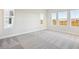 Bright bedroom with gray carpet, three large windows, and white walls at 10324 Longmeadow Ave, Parrish, FL 34219