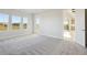 Primary bedroom with large windows, gray carpet, and access to the kitchen at 10324 Longmeadow Ave, Parrish, FL 34219