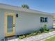 Charming exterior view featuring a light blue exterior wall, a yellow back door, and beautiful landscaping at 120 Chesapeake Ave, Tampa, FL 33606