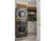 Laundry room with stacked washer and dryer, custom cabinetry, and open shelving at 120 Chesapeake Ave, Tampa, FL 33606