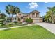 Elegant two-story home with a manicured lawn, lush landscaping, and a welcoming double-door entrance at 19300 Lonesome Pine Dr, Land O Lakes, FL 34638