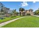 Sprawling front lawn with landscaped garden, palm trees, and a two story home with balcony and two car garage at 19300 Lonesome Pine Dr, Land O Lakes, FL 34638