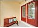 Close up of a red double door with glass, a wooden bench and two pillows on a covered front porch at 19300 Lonesome Pine Dr, Land O Lakes, FL 34638