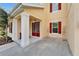 Covered entrance with red double door, white columns and flower pot accents, next to manicured landscaping at 19300 Lonesome Pine Dr, Land O Lakes, FL 34638