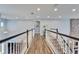 Bright hallway featuring wood-look tile floors, railing overlooking the living room, and neutral wall color at 19300 Lonesome Pine Dr, Land O Lakes, FL 34638