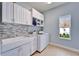 A functional laundry room with modern appliances, a window, granite countertops, and tiled backsplash at 19300 Lonesome Pine Dr, Land O Lakes, FL 34638