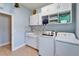 A well-lit laundry room featuring modern washer and dryer units, cabinetry, granite countertops, and tiled backsplash at 19300 Lonesome Pine Dr, Land O Lakes, FL 34638