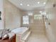A luxurious bathroom with a large soaking tub, tiled shower with glass surround, and recessed lighting at 19300 Lonesome Pine Dr, Land O Lakes, FL 34638