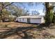 View of the home's white exterior and backyard, featuring a spacious lawn and mature trees at 3432 Danny Bryan Blvd, Tampa, FL 33619