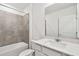 Bright bathroom featuring a tub with tile surround and a vanity with a quartz countertop at 10607 Hidden Banks Gln, Parrish, FL 34219