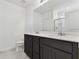 Bathroom with dark vanity, double sinks, and a large mirror at 12744 Wanderlust Pl, Parrish, FL 34219