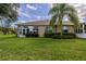 Home's back elevation, showcasing sunroom and green lawn at 1940 Inverness Greens Dr # 1940, Sun City Center, FL 33573