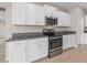 Modern kitchen with white cabinets, granite countertops, and stainless steel appliances at 5474 Leslie Canyon Dr, Wimauma, FL 33598