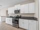 Modern kitchen with white cabinets, granite countertops, and stainless steel appliances at 5474 Leslie Canyon Dr, Wimauma, FL 33598