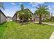 Landscaped yard with lush grass, palm trees, and a covered porch at 10012 Sage Creek Dr, Ruskin, FL 33573