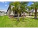 Landscaped yard with lush grass, palm trees, and a covered porch at 10012 Sage Creek Dr, Ruskin, FL 33573