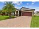 Single-Gathering home with brick driveway, two-car garage and palm trees at 10012 Sage Creek Dr, Ruskin, FL 33573