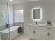 Bright bathroom with a freestanding tub, glass shower, and modern vanity with lighted mirror at 5308 Cedarshake Ln, Valrico, FL 33596
