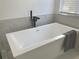 Close up of a modern white bathtub with sleek fixtures and marble tile surround at 5308 Cedarshake Ln, Valrico, FL 33596
