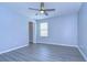 A bedroom with blue walls, grey wood-look flooring, ceiling fan, and a walk-in closet at 5365 Shasta Daisy Pl, Land O Lakes, FL 34639