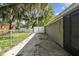 Side yard with concrete patio, white gate, and chain link fence at 7024 Filbert Ln, Tampa, FL 33637