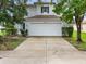 Two-story house front elevation with a white double-car garage and landscaping at 18933 Sunterra Dr, Land O Lakes, FL 34638