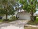 Two-story house with a white double garage door, nicely landscaped yard, and a neatly paved driveway at 18933 Sunterra Dr, Land O Lakes, FL 34638
