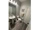 Stylish powder room with pedestal sink, gray walls, and wood-look tile floor at 18135 Canal Pointe St, Tampa, FL 33647