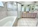 Large bathroom featuring soaking tub, glass shower, double vanity with tile flooring at 13451 Knotty Ln, Hudson, FL 34669