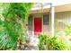 Red front door entrance with lush tropical landscaping at 758 Pine Run Dr # 758, Osprey, FL 34229