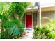 Inviting red front door entryway, surrounded by lush tropical landscaping at 758 Pine Run Dr # 758, Osprey, FL 34229