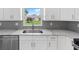 White kitchen cabinets, grey backsplash and marble countertops at 10317 Gulfstream Blvd, Englewood, FL 34224