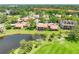 Aerial view showcases the community's beautiful landscaping, serene pond, and inviting pool nestled among tile-roofed homes at 1314 Pelican Creek Xing # 1314, St Petersburg, FL 33707