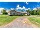 Ranch style home with a gravel driveway and lush lawn at 36431 Florrie Mae Ln, Dade City, FL 33523