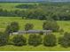 An aerial view shows this home and expansive manicured lot with mature trees, and distant fields at 34868 Prospect Rd, Dade City, FL 33525