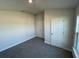 Spacious bedroom with single door and grey carpet at 13260 Ogden Glade Rd, Dade City, FL 33525