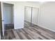 Bright bedroom showcasing a closet with mirror doors and durable gray laminate floors at 2501 Lonigan Pl, Sun City Center, FL 33573
