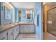 Bright bathroom with double sinks, vanity, mirrors, and a tiled shower at 5733 Pawnee St, Zephyrhills, FL 33542