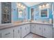 Bright bathroom features double sinks with vanity, light blue walls, and a unique cabinet at 5733 Pawnee St, Zephyrhills, FL 33542
