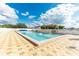 Outdoor pool with a paver deck, lounge chairs, and a covered seating area on a bright, sunny day at 5733 Pawnee St, Zephyrhills, FL 33542